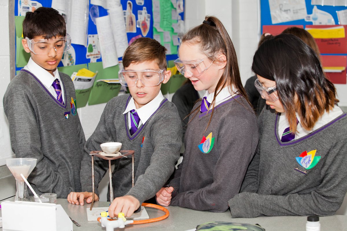 4 students in a science lesson doing an experiment with a bunsen burner