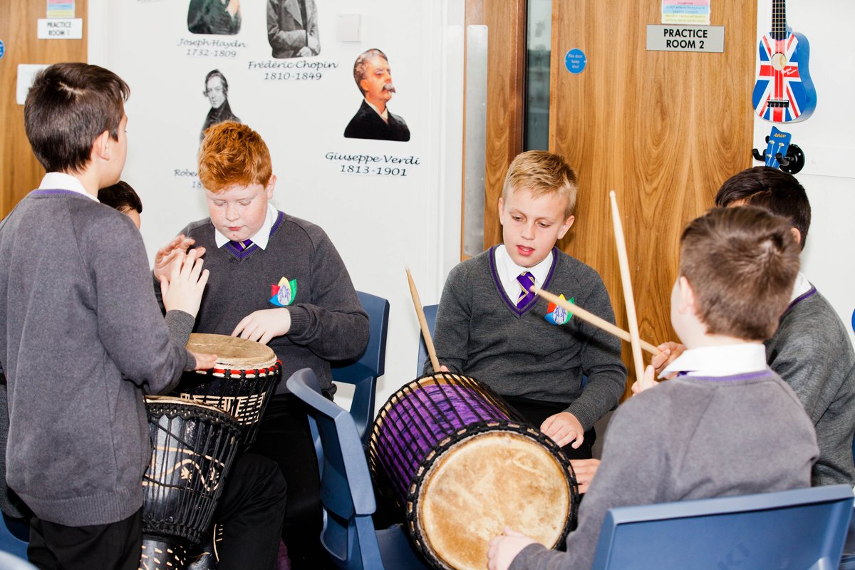 5 students sat in a circle playing handheld drums