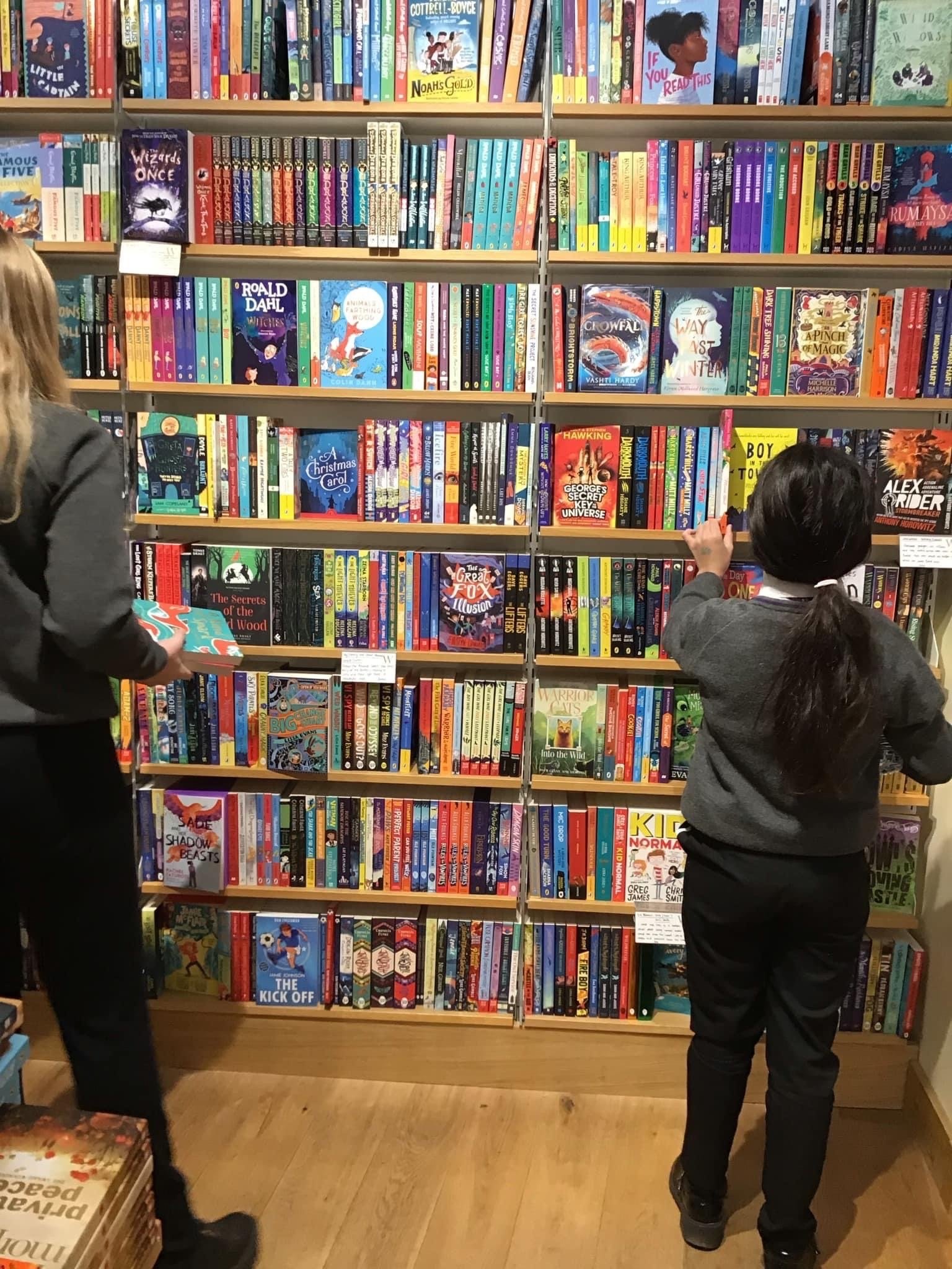 2 students stood in front of a wall of books