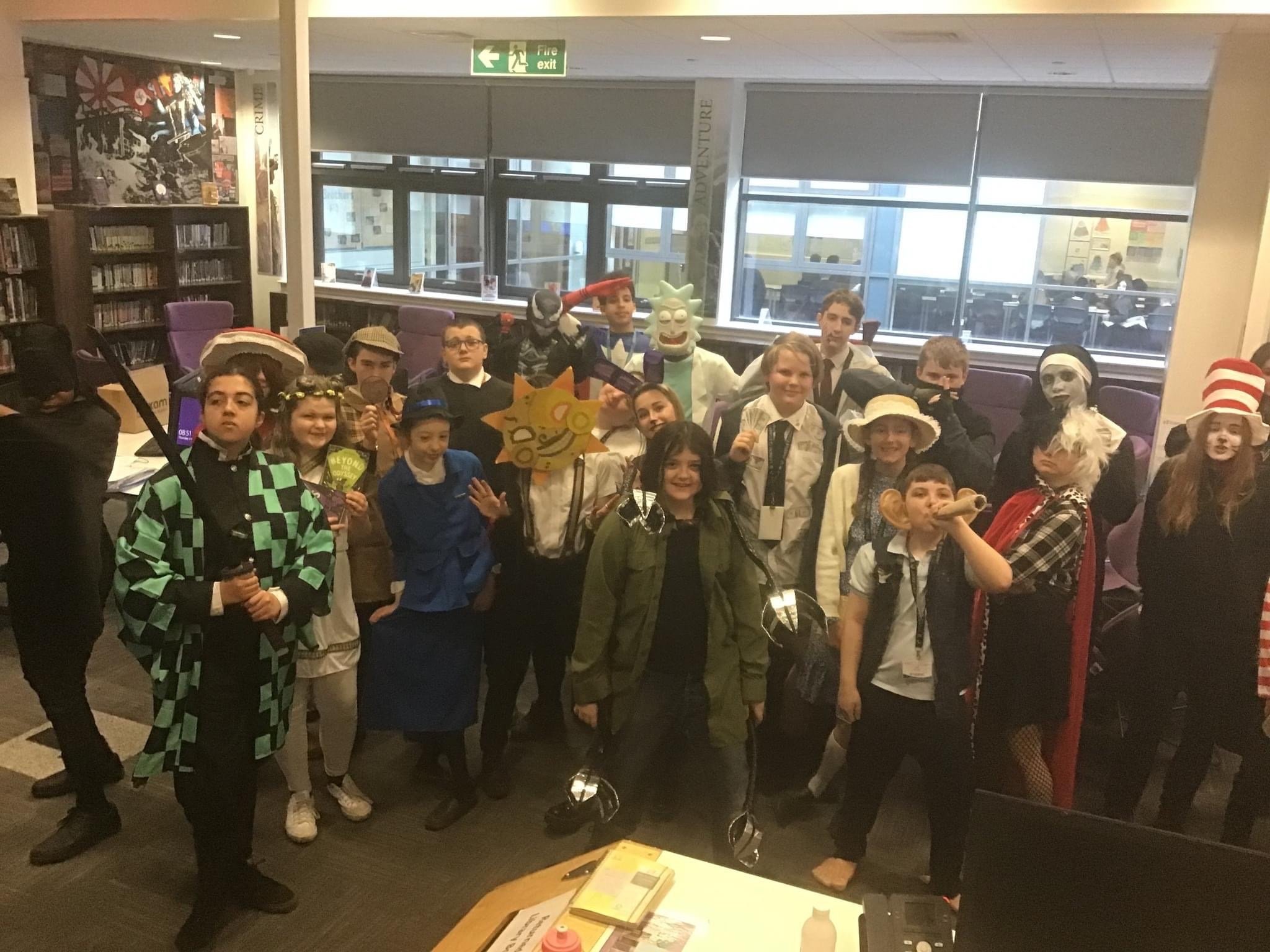 A group of about 15 students stood together, they are wearing a variety of costumes for world book day