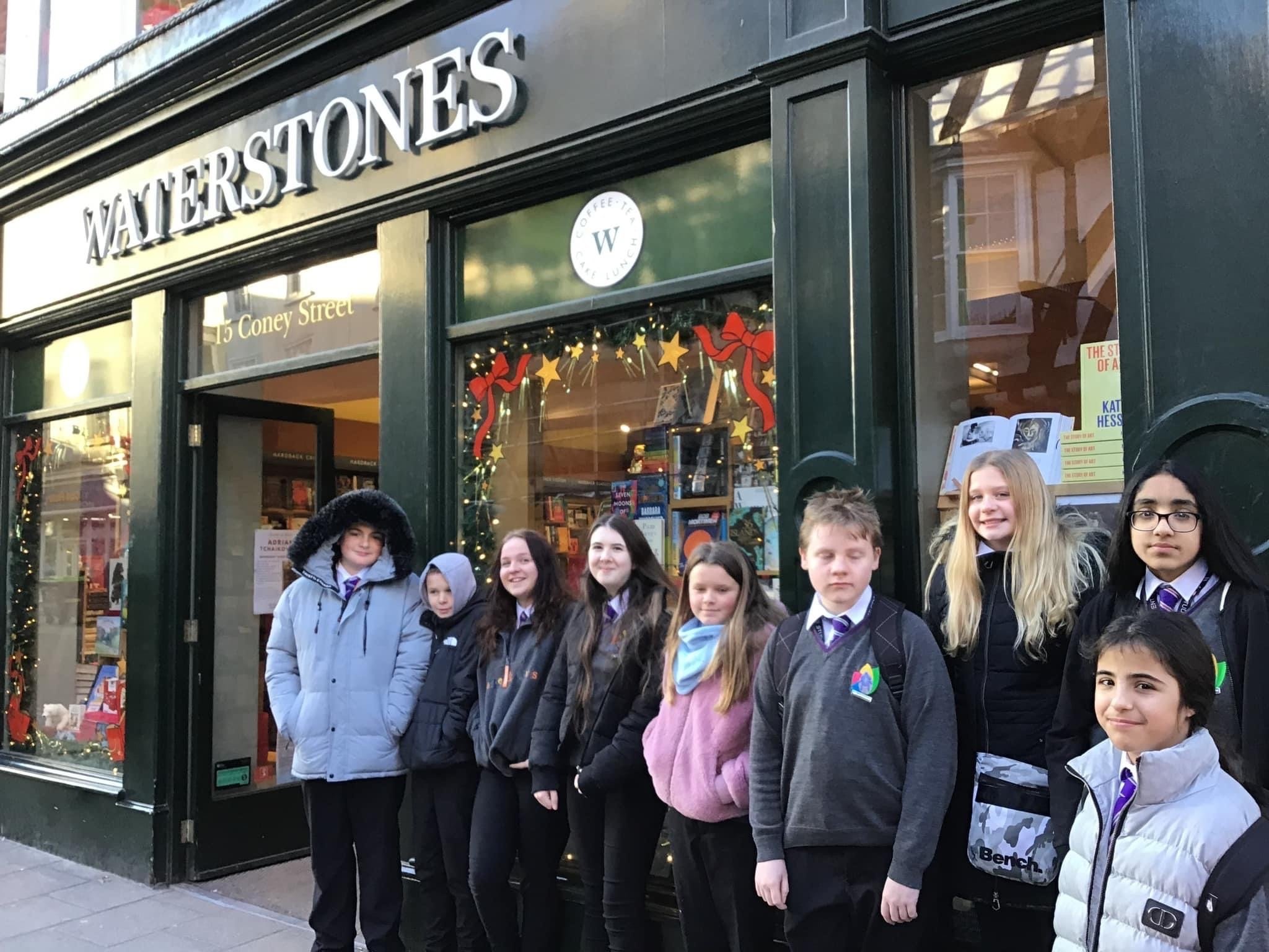 A group of 9 students stood outside of a book shop, while on a school trip