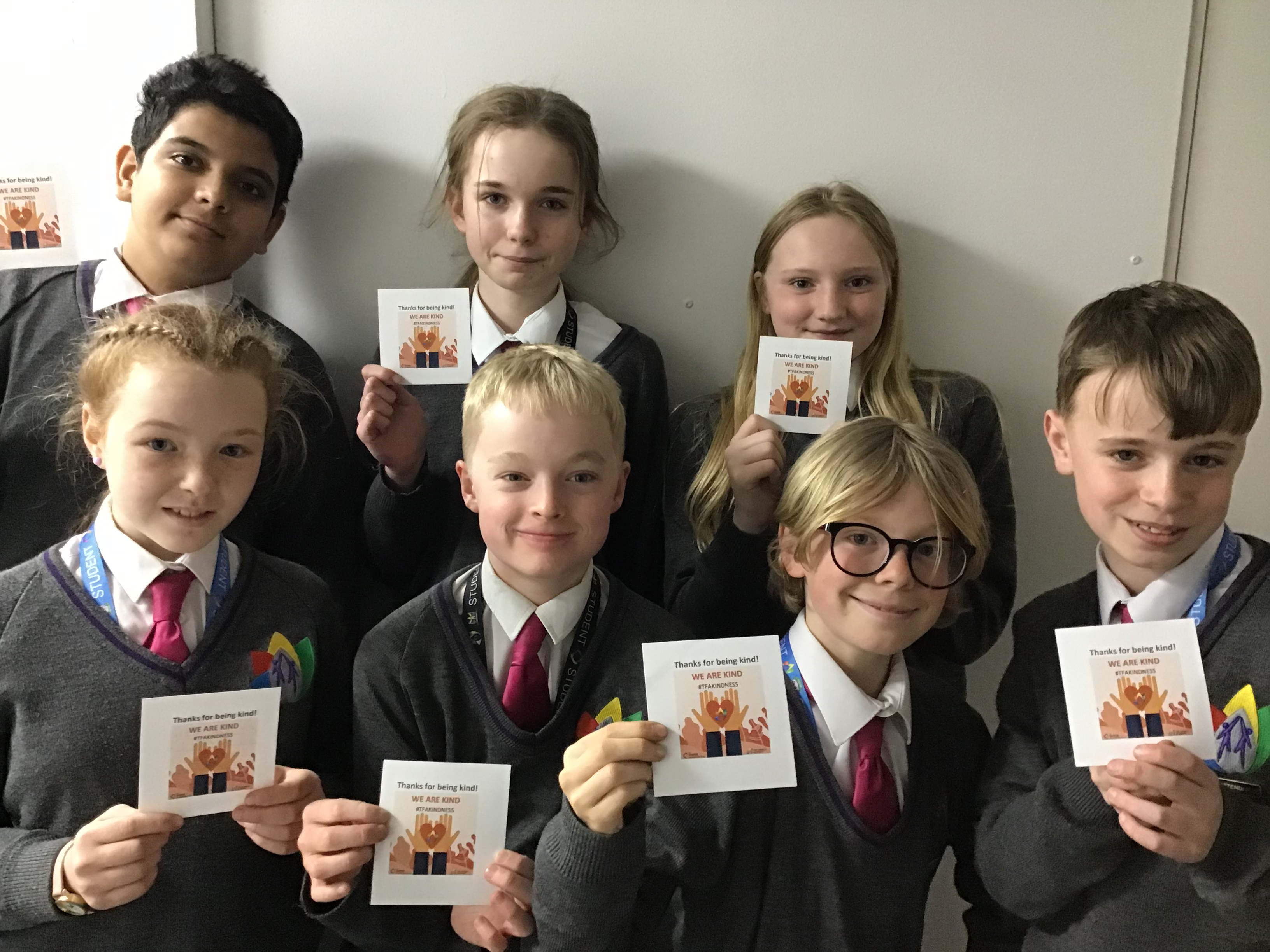 7 students stood together and holding a piece of paper up for the kindness committee