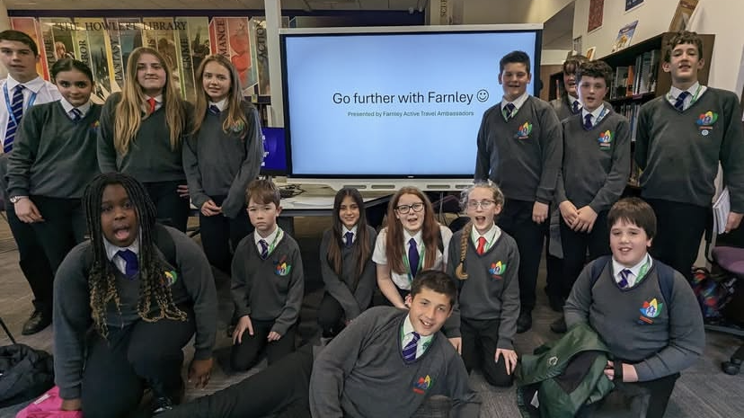A group of about 15 students all posing for a picture together. Some are stood at the back, others are sat on the floor in front