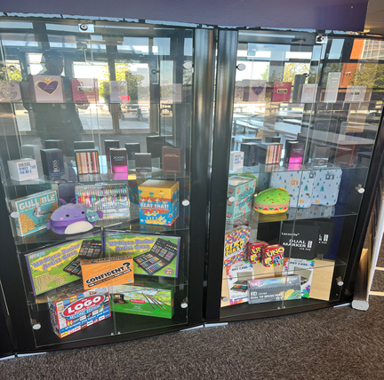 A glass display cabinet, it’s filled with a variety of prizes & colourful boxes