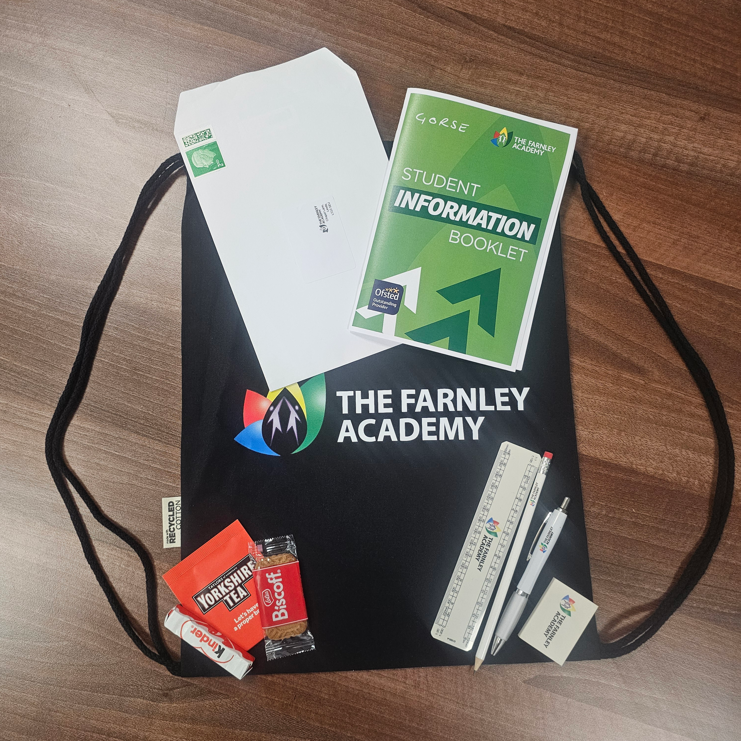 A cloth bag with the Farnley academy logo, there are also a few small posters & welcome flyers sat on top of the bag